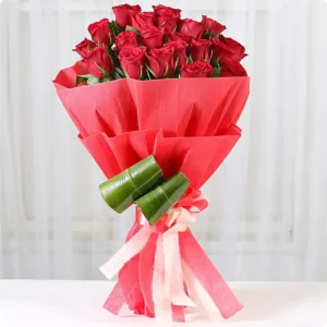 Bouquet of 25 fresh red roses wrapped in red paper with green leaf décor and ribbon bow